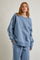 woman wearing a light blue oversized sweatshirt with lace trim details on the sleeves and matching bottoms