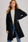 woman wearing a black long cardigan over a light gray sweater and blue jeans