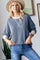 woman wearing a blue ribbed long sleeve sweater with white detailing and a wide brim hat, paired with blue jeans