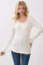 woman wearing a cream long sleeve waffle knit top with button detail and relaxed fit paired with blue jeans