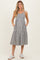 woman wearing a striped maternity sundress with pockets and buttons, standing in casual sneakers