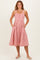 woman wearing a red and white striped sundress with a button-down front and pockets, standing with hands in pockets