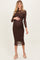 woman wearing a brown polka dot maternity dress with long sleeves and a fitted silhouette, showing her baby bump
