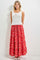 woman wearing a white ribbed tank top with lace trim and a red floral maxi skirt