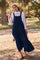 woman wearing a navy blue tiered maxi dress with button details and a white long sleeve top, standing on a swing