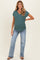 woman wearing a teal maternity top with short sleeves and a v-neck, paired with light blue flared jeans and showing a baby bump
