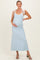 woman wearing a light blue maternity maxi dress with white straps and holding her baby bump