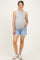 woman wearing a gray sleeveless maternity top and denim shorts, showcasing her baby bump