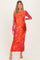 woman wearing a vibrant orange and pink long sleeve maternity dress with a fitted silhouette and abstract design