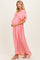 woman wearing a pink v-neck short sleeve maternity maxi dress, cradling her baby bump