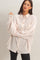 woman wearing a light pink oversized button-up shirt with a front pocket and long sleeves, styled with black leggings
