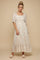woman wearing a beige floral maxi dress with puff sleeves and a tiered skirt, standing on a neutral background