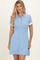 woman wearing a sky blue short sleeve polo dress with a white collar and buttons