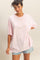 woman wearing a light pink oversized t-shirt with short sleeves and casual denim shorts