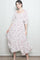 woman wearing a white floral maxi dress with smocked bodice and puff sleeves, standing against a plain background