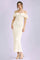 woman wearing a cream off-the-shoulder maxi dress with ruffle sleeves and a tie detail, standing against a soft background