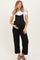 woman wearing a black maternity jumpsuit with a white t-shirt and holding her baby bump