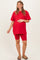 woman wearing a red oversized t-shirt and matching biker shorts, showing her baby bump