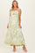woman wearing a floral print maternity maxi dress with a ruffled neckline and a subtle baby bump visible