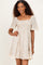 woman wearing a beige and white striped short sleeve dress with a smocked bodice and lace trim at the hem