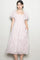 woman wearing a light pink floral midi dress with puff sleeves and pockets