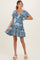 woman wearing a blue floral short sleeve maternity dress with a ruffled hem and a v-neckline