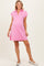 woman wearing a pink short sleeve maternity polo dress with a relaxed fit and side slits, showcasing her baby bump