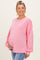 woman wearing a pink oversized maternity sweatshirt and holding her baby bump