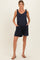 woman wearing a navy blue maternity romper with adjustable tie straps and side pockets, highlighting her baby bump