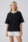 woman wearing a black oversized t-shirt with a white collar paired with white shorts