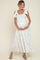 woman wearing a floral maternity maxi dress with bow straps, holding her baby bump and smiling