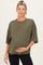 woman wearing an olive green oversized maternity top with a textured hem and holding her baby bump