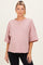 woman wearing a mauve oversized maternity sweatshirt with raw hem and short sleeves, showing her baby bump