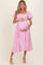 woman wearing a pink and white gingham maternity dress with puff sleeves and holding her baby bump