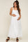woman wearing a white maternity maxi dress with button details and holding her baby bump