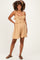 woman wearing a tan maternity romper with ruffle and smocked details, styled with sandals and curly hair