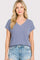 woman wearing a light purple v-neck short sleeve top with relaxed fit and rolled sleeves paired with distressed denim shorts