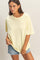 woman wearing a light yellow oversized t-shirt and distressed denim shorts