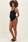 woman wearing a black maternity swimsuit with colorful straps and a visible baby bump