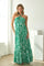 woman wearing a green and white floral print maxi dress with a halter neck and tiered hem