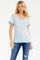 woman wearing a white floral print top with blue trim and short sleeves, paired with denim jeans