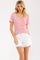 woman wearing a pink and white striped short sleeve tee with button details and white denim shorts