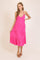 woman wearing a bright pink halter-style maxi dress with tiered ruffles and sandals