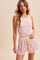woman wearing a pink and white striped tank top and matching shorts with yellow trim