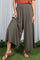 woman wearing olive green wide-leg pants with a high waistband and pleated details, paired with brown slide sandals
