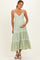 woman wearing a light green maternity maxi dress with adjustable straps and a tiered skirt, holding her baby bump