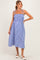 woman wearing a blue and white gingham maternity dress with adjustable straps and a visible baby bump