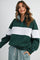 woman wearing a green and grey color block quarter zip sweatshirt with checkered pants