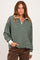 woman wearing a dark green and white striped long sleeve quarter zip top with a relaxed fit and white collar
