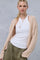 woman wearing a beige cable-knit cardigan over a white tank top and olive green pants, styled with layered necklaces